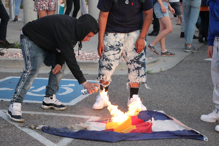 A protester sets fire to the Colorado state flag outside the immigrant detention center. A larger group of protesters pleaded with the group at the facility's entrance to retreat, saying their tactics put the rest of the rest of the participants in jeopardy.